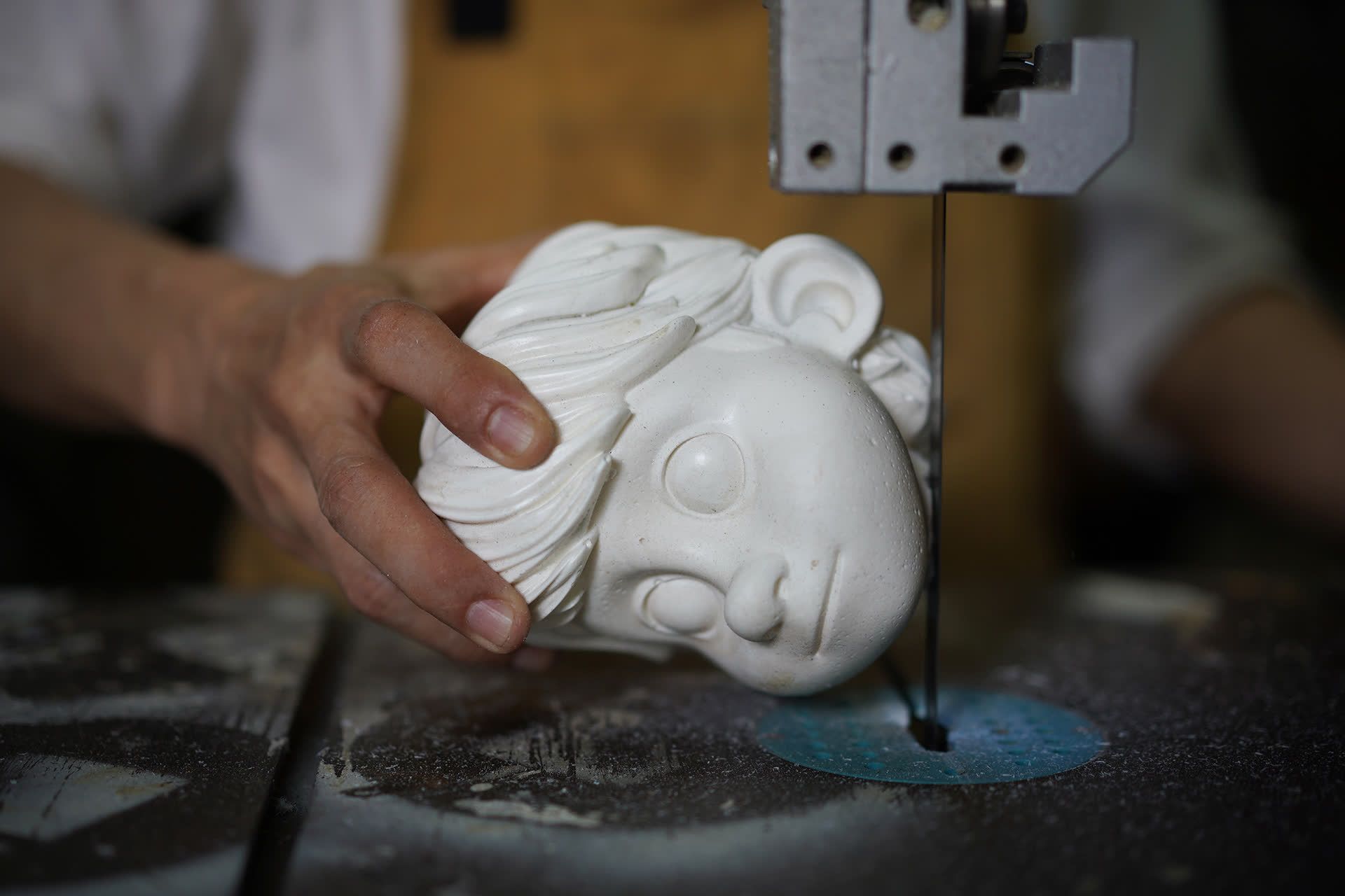 Mr Yeo filing the rough edges of a puppet head in his workshop.
