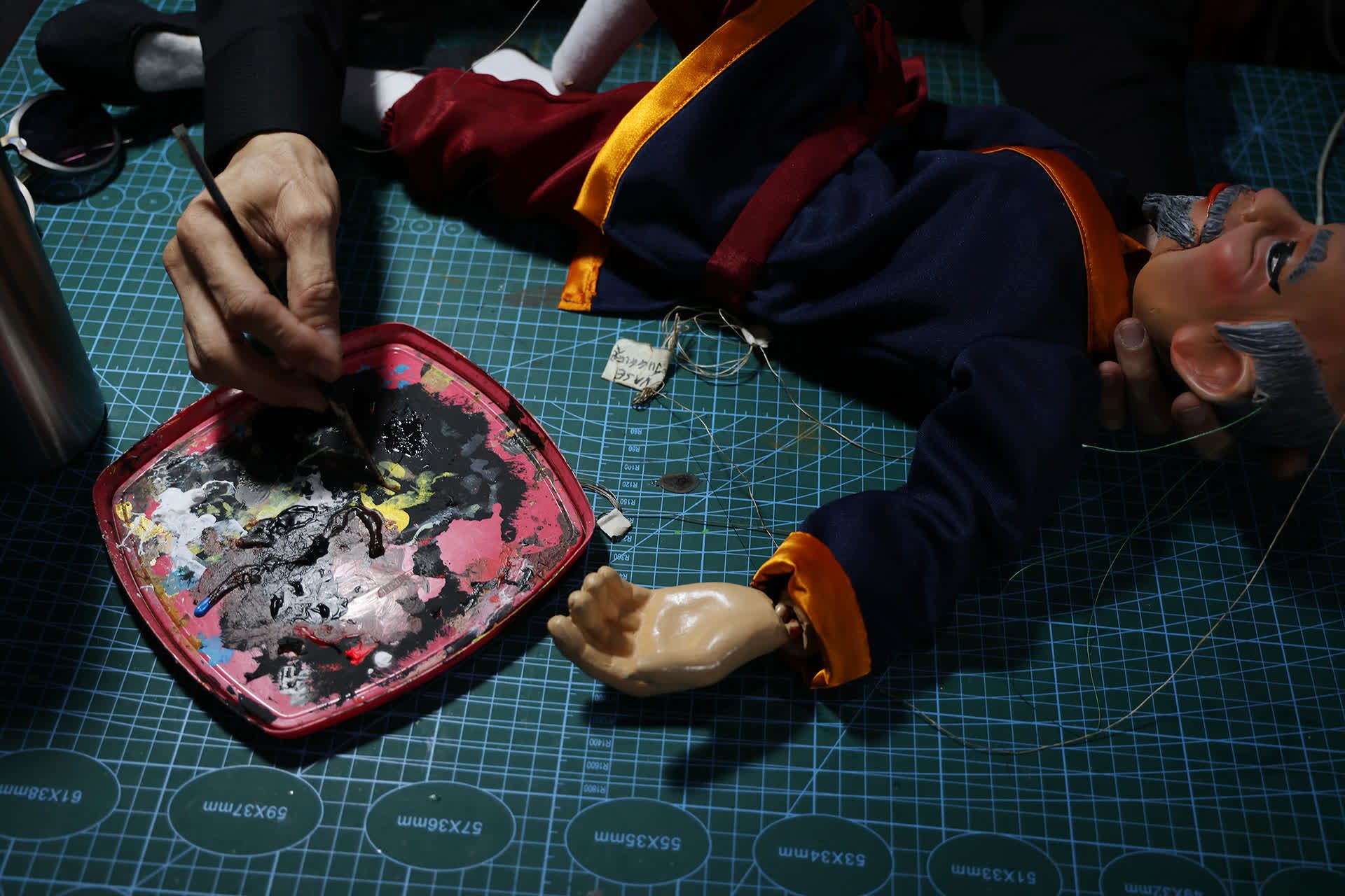 Here, he is touching up the paint on a puppet.